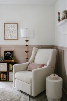 a living room with a chair, lamp and bookshelf on the wall next to a window