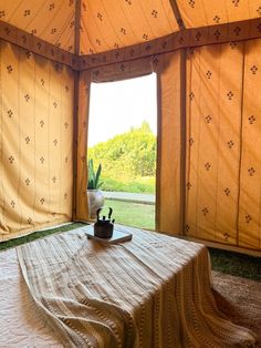 a bed in a tent with a table and potted plant on top of it