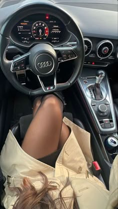 a woman is sitting in the driver's seat of a car with her feet on the steering wheel