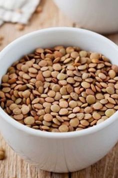 a white bowl filled with nuts on top of a wooden table