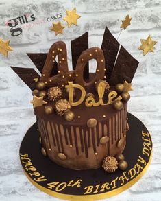 a chocolate birthday cake with gold stars and the number 40 on top is sitting on a black plate