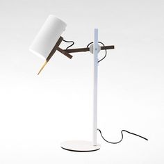 a desk lamp with a white shade on it and a wooden stick sticking out of the base