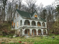 an old abandoned house in the woods with lots of windows and balconies on it