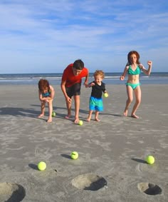 a family playing with balls on the beach