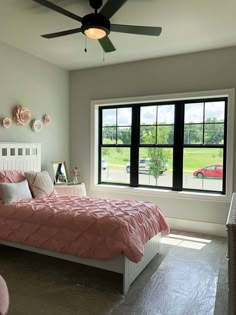 a bed room with a neatly made bed and a large window overlooking the field outside