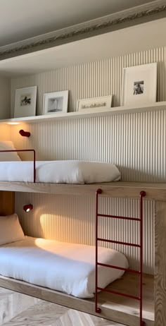 two bunk beds with white sheets and pillows in a room that looks like it has been built into the wall