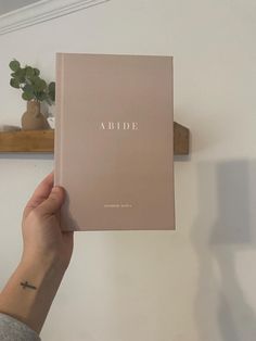 a person holding up a book with the word bride on it in front of a white wall