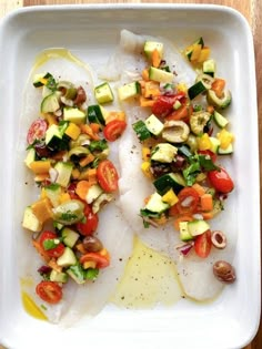 a white plate topped with fish covered in veggies