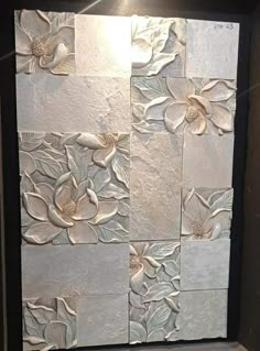 a white tile wall with flowers and leaves on it