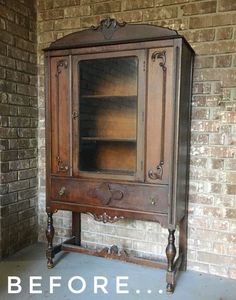 an old wooden cabinet with glass doors in front of a brick wall that says before