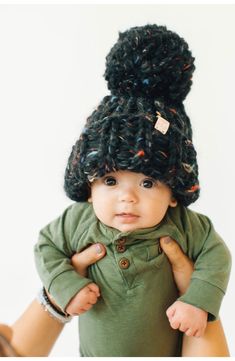 a baby is wearing a black hat and green shirt