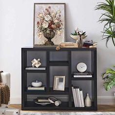 a living room with a book shelf and potted plant on the side table in front of it