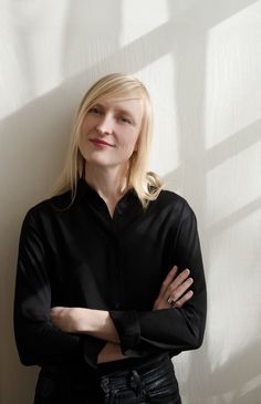 a woman standing with her arms crossed in front of a wall