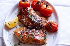 a white plate topped with meat and tomatoes