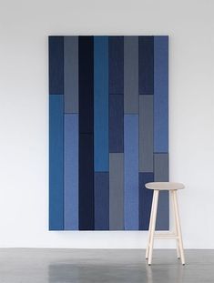 a chair sitting in front of a painting on the wall with blue and grey stripes