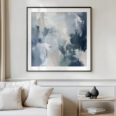 a living room with a white couch and blue painting on the wall above it's coffee table