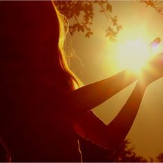 the sun is shining brightly over a woman's shoulder and arm as she holds her cell phone up to her ear