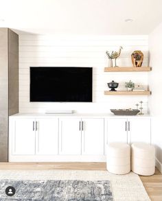 a flat screen tv mounted to the side of a white wall in a living room