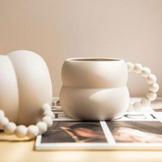 a white vase sitting on top of a wooden table next to a beaded bracelet