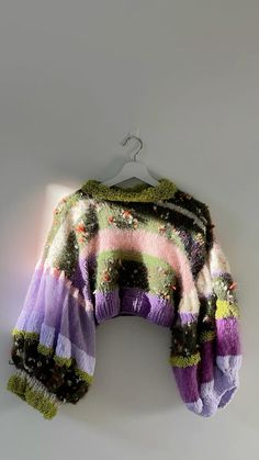 a multicolored sweater hanging on a white wall