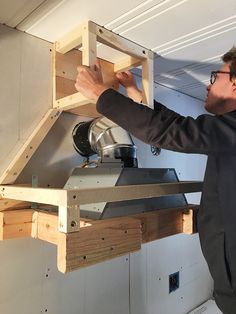 a man is working on some kind of shelf in the kitchen with his handmade stove