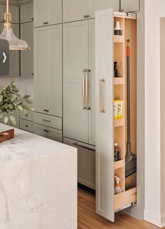 an open cabinet in the middle of a kitchen with marble counter tops and wooden flooring