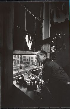 black and white photograph of man looking out window