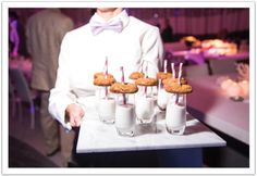 a person holding a tray with desserts and drinks on it in front of them