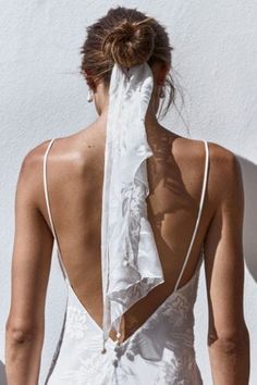 the back of a woman wearing a white dress with ruffles on her neck