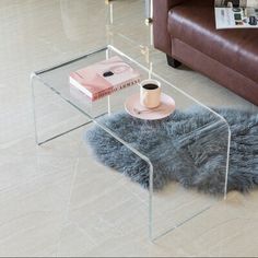 a glass table with a coffee cup and saucer on it next to a couch