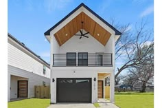 a white two story house with a black garage door on the front and second floor