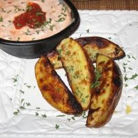 some food is laying out on a white tablecloth and next to a bowl of dip