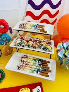 an assortment of desserts displayed on three tiered trays with balloons in the background