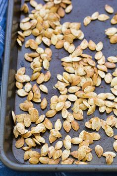 pumpkin seeds on a baking sheet ready to go into the oven in the oven pan