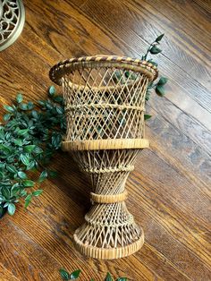 a wicker vase sitting on top of a wooden table next to a potted plant