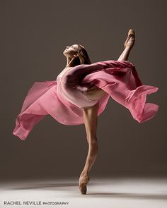 a woman in a pink dress is dancing with her arms spread out to the side