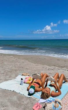 a woman laying on top of a beach next to the ocean