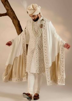 Featuring our infamous Kashmiri jamawar embroidered sherwani in dirty ivory color with floral design details. The piece is then highlighted with dabka and zari. Paired with a matching hand-embroidered stole and safa. Groom Engagement Outfit Indian, Engagement Outfits Indian, White Sherwani, Indian Wedding Clothes For Men, Drape Sarees, Embroidered Sherwani, Ridhi Mehra, Sherwani Groom, Draped Saree