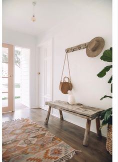 a wooden bench sitting in front of a door next to a rug and potted plant