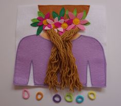 a piece of art made out of felt with flowers on the head and beads around it