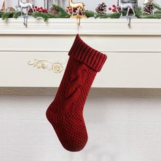 a red knitted christmas stocking hanging from a mantel