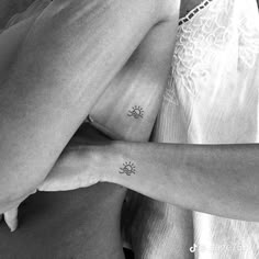 two women with matching tattoos on their arms, one is holding the other's arm