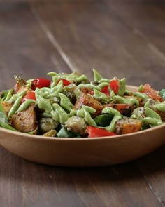 a wooden bowl filled with vegetables on top of a table