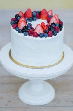 a white cake topped with berries and blueberries