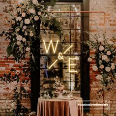 a table topped with a cake next to a window covered in flowers and greenery