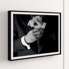 a black and white photo of a man in a suit adjusting his tie on the wall