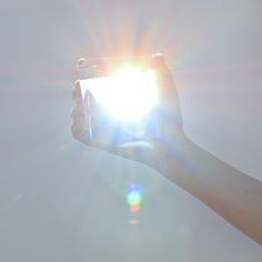 someone is holding up their phone to take a photo with the sun in the background