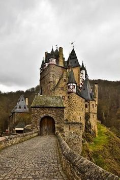 an old castle on top of a hill with a stone walkway leading up to it