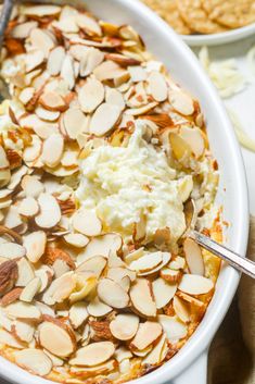 a bowl filled with mashed potatoes and topped with almonds next to crackers