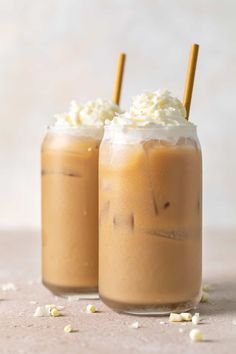 two drinks with whipped cream on top sit next to each other